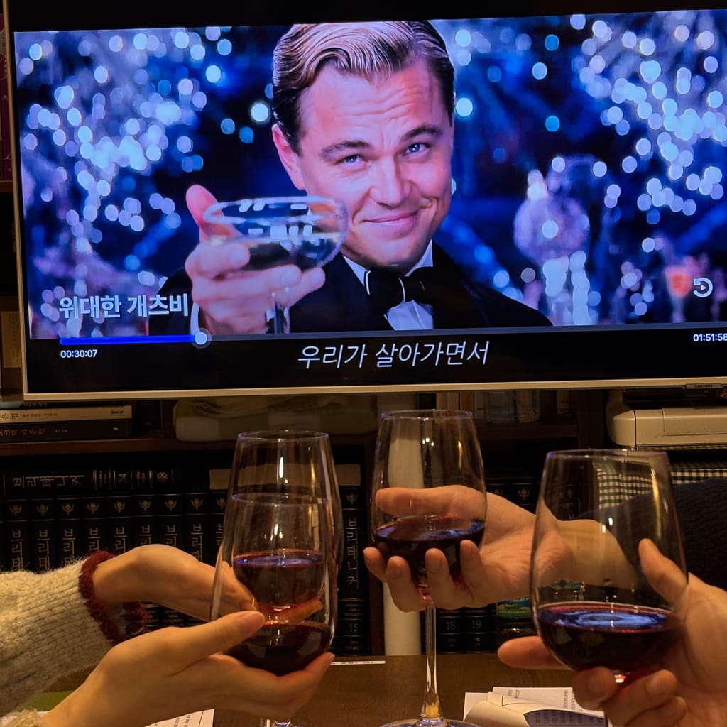 책방 스크린에 「위대한 개츠비」를 틀어 놓고, 와인잔을 함께 부딪치는 손들