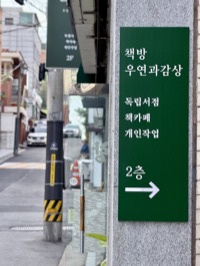 건물 입구의 초록 안내판: 책방 우연과감상, 독립서점·책카페·개인작업, 2층